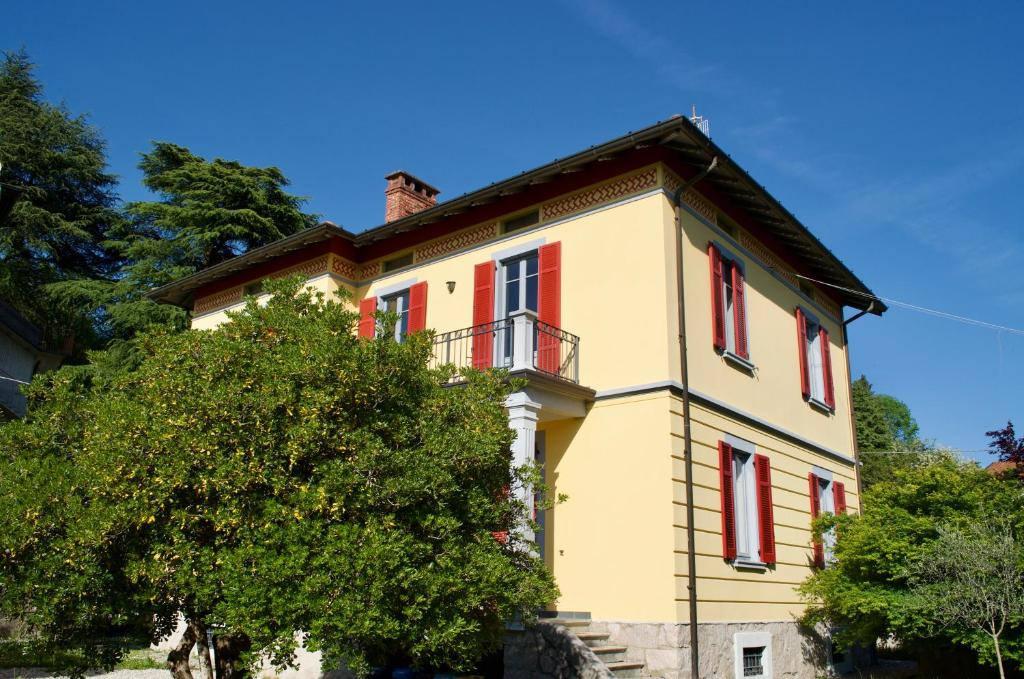 a yellow house with red windows and a balcony at Casa Corten, Vista Lago in Cerro Lago Maggiore