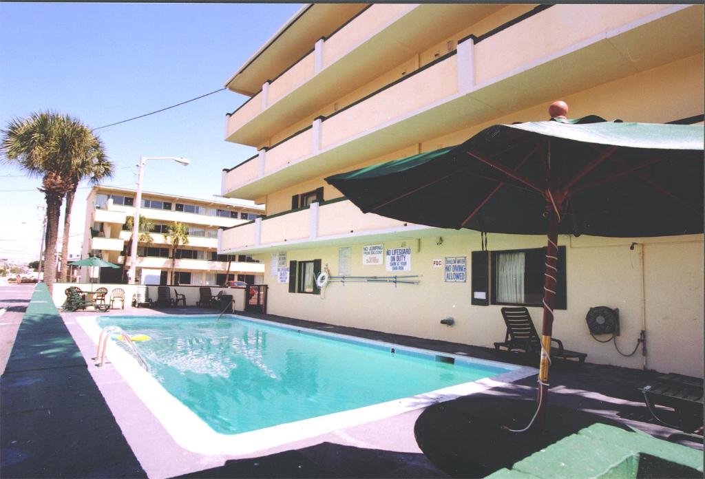 a swimming pool with an umbrella next to a building at Happy Holiday Motel in Myrtle Beach