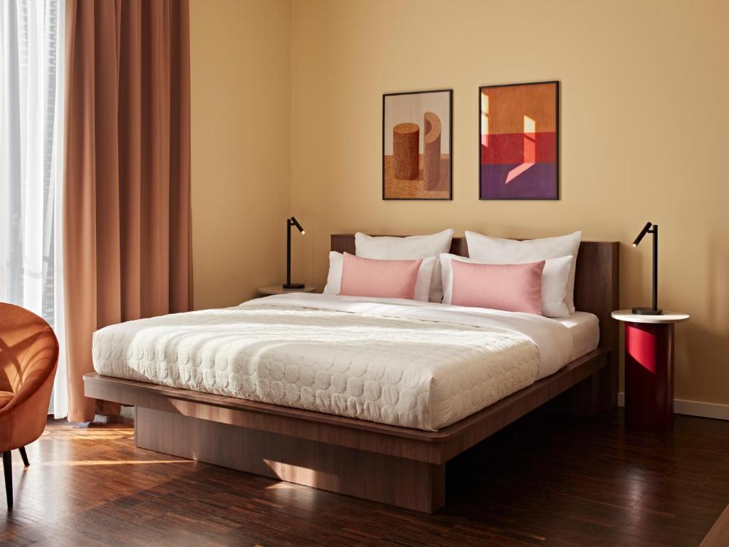 a bedroom with a large bed with pink pillows at Numa Berlin Weinmeister in Berlin