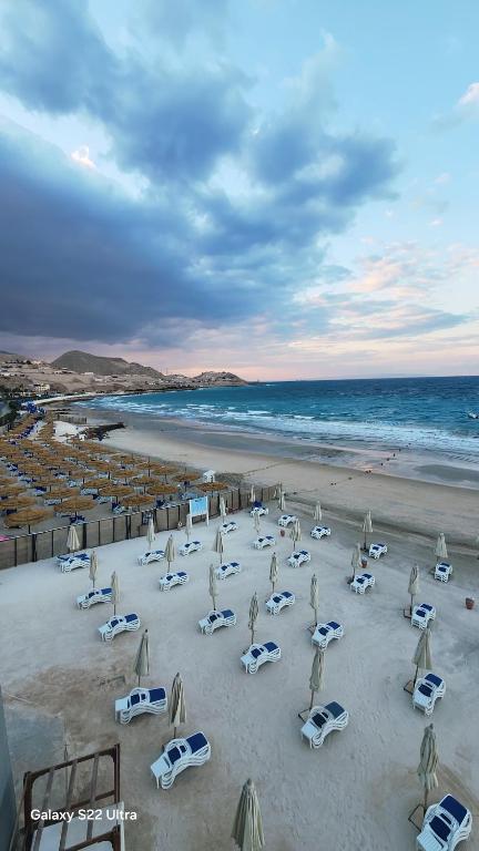 a beach with chairs and umbrellas and the ocean at Porto Sokhna Marina Towers sea view in Ain Sokhna