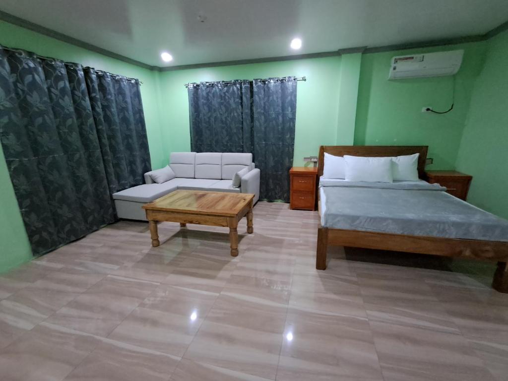 a bedroom with a bed and a couch and a table at JMM Guest House in Panglao Island