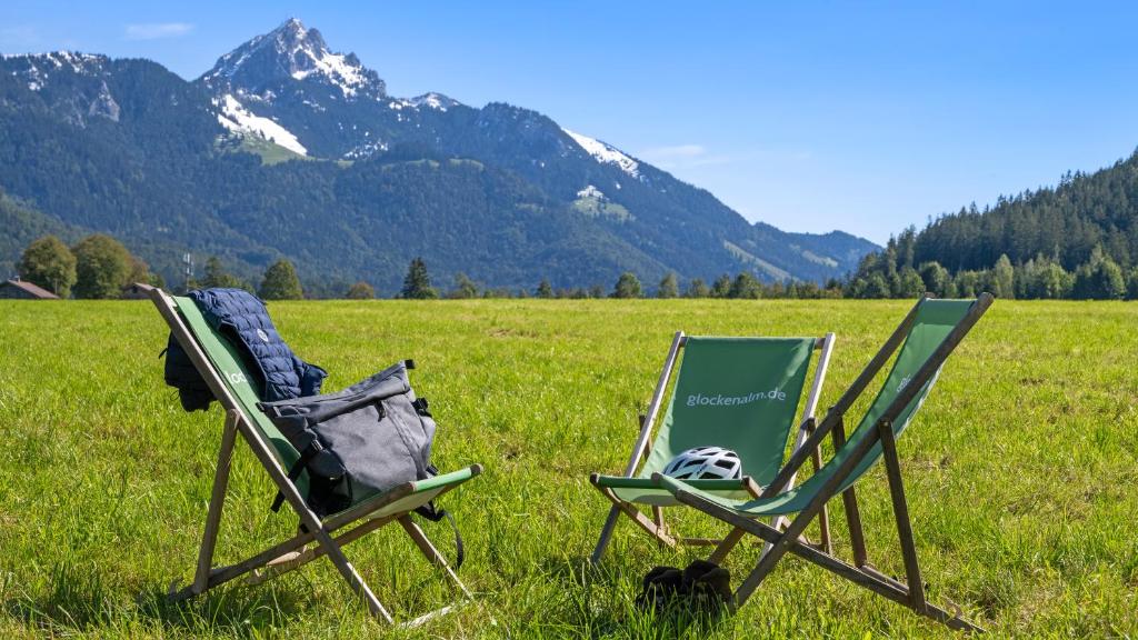 two lawn chairs in a field with mountains in the background at NATURAMA Glockenalm in Fischbachau