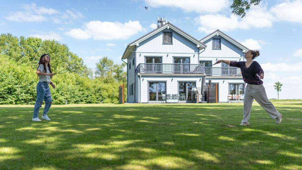 two women playing frisbee in front of a house at Lodge54 in Sankt Peter-Ording