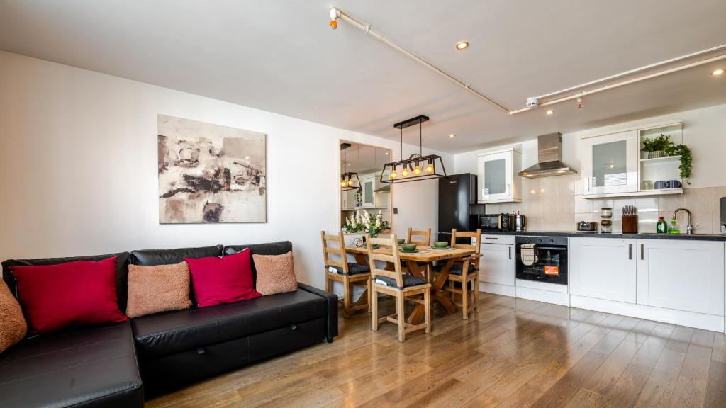 a living room with a black couch and a kitchen at Group-Friendly Flat - 3 Beds, a Sofa Bed & Parking in Andover