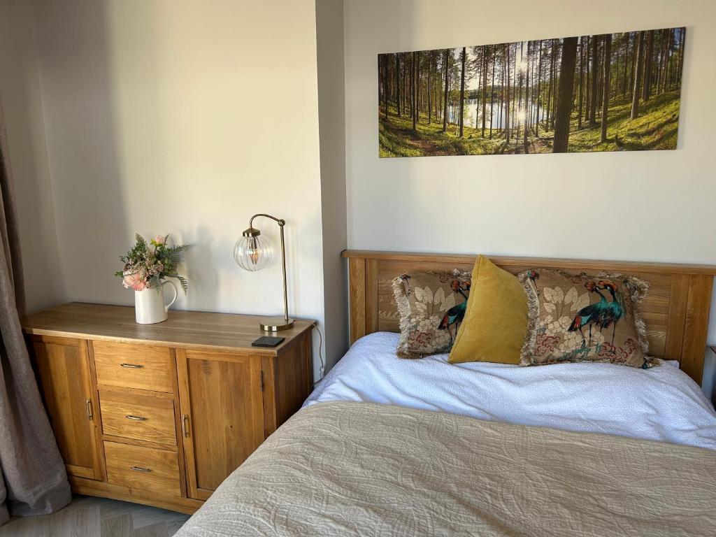 a bedroom with a bed and a wooden dresser at Sunny Garden WFH Retreat with Private Entrance and Parking near NEC BHX JLR in Solihull