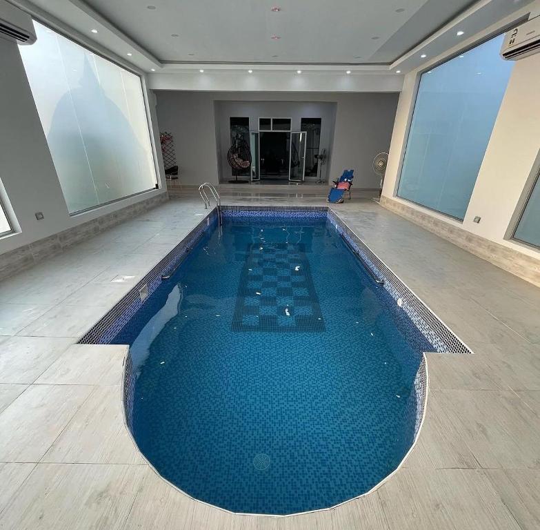 a large swimming pool in a room with large windows at استراحة العمران in Murayjāt