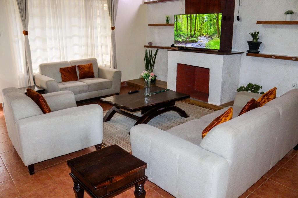 a living room with two white couches and a tv at Larami House Narok in Narok