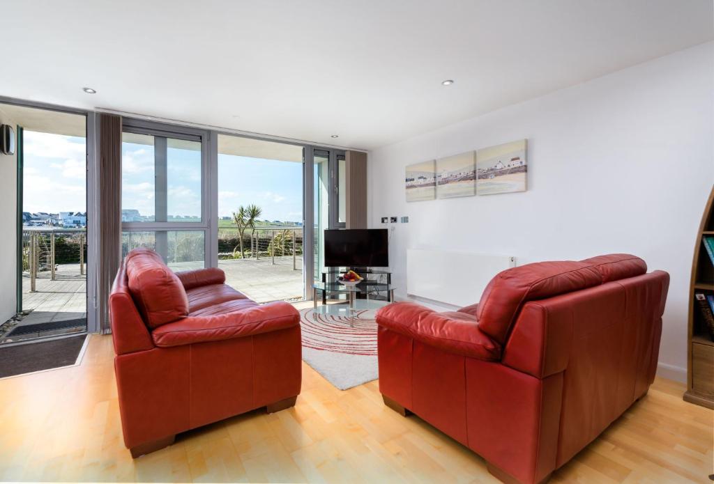 a living room with two red chairs and a television at 11 Zinc in Newquay in Newquay
