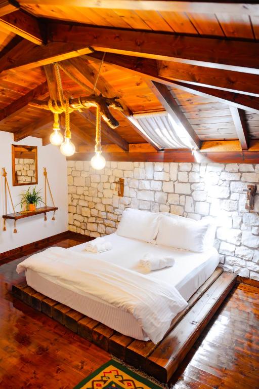 a large white bed in a room with a stone wall at Anhel Hotel in Berat