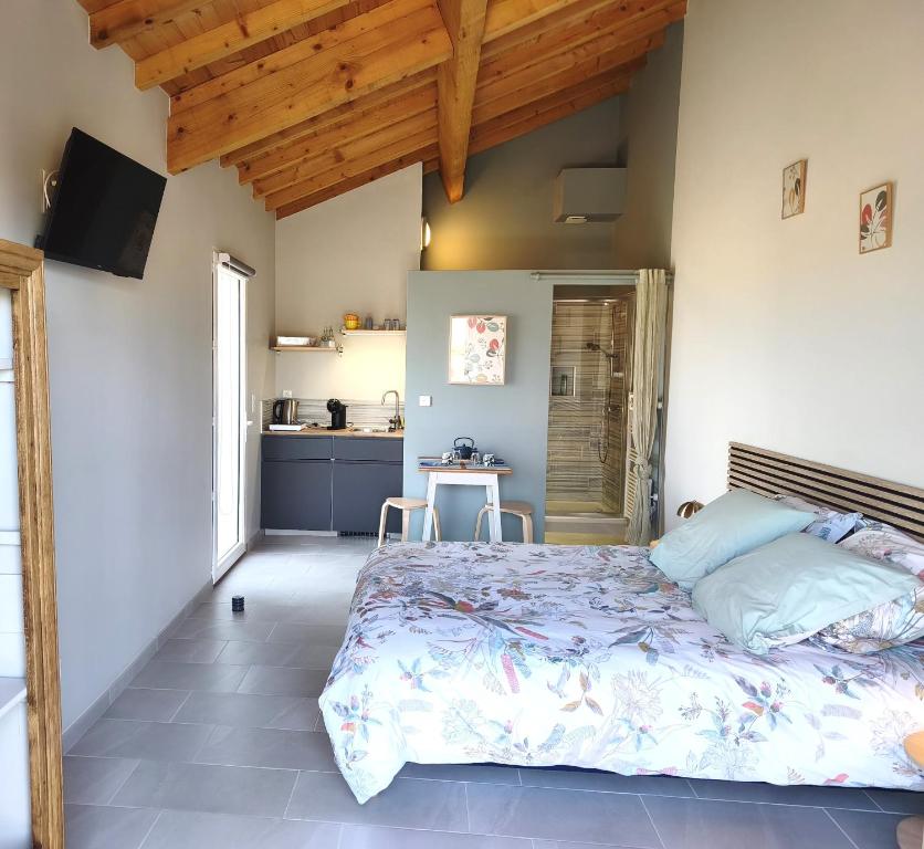a bedroom with a large bed and a kitchen at Chambre indépendante, sdb privée in Saulcet