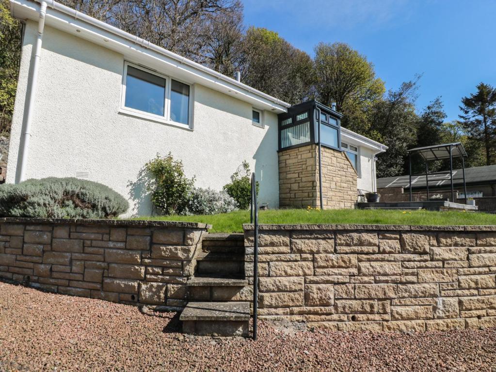 a home with a brick retaining wall and a house at Crown Cottage in Dunfermline