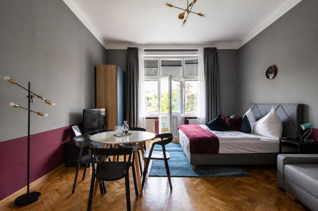 a bedroom with a bed and a table and a bed and a table and chairs at Garden Apartments in Prague