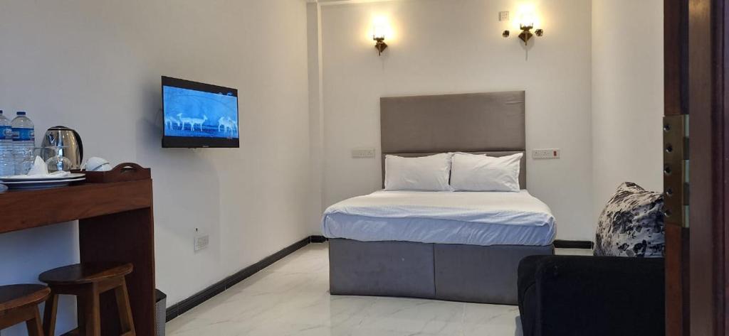 a small bedroom with a bed and a tv on the wall at Royal Horizon in Nuwara Eliya
