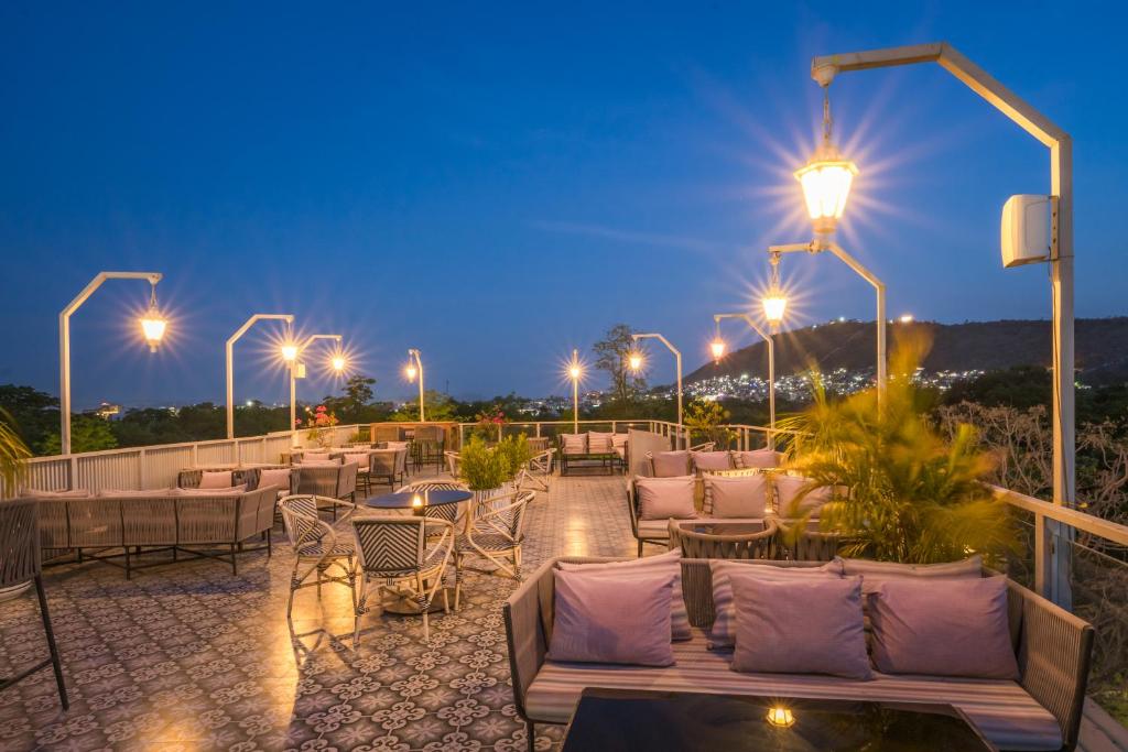 a patio with chairs and tables and lights at night at Tripli Hotels Shourya Residency in Udaipur