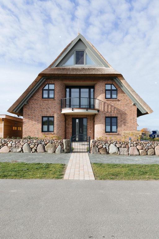 a large brick house with a gambrel roof at SunCliff Lodge - exklusive private Sauna, Sanarium, Kamin und Meerblick in Dranske