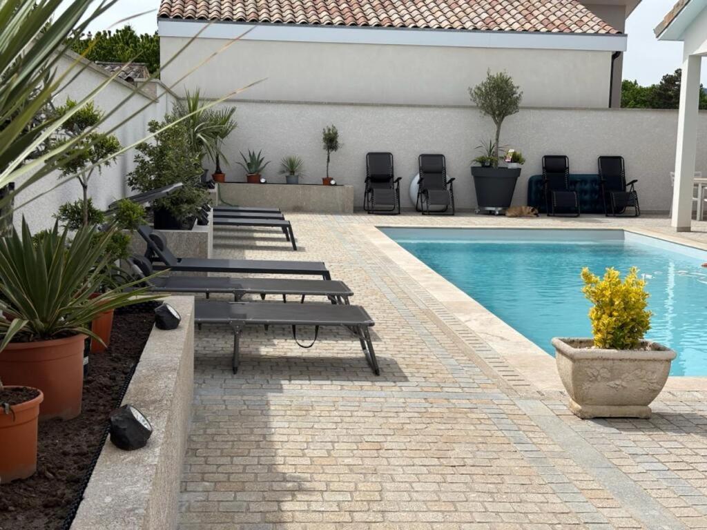 a pool with benches and chairs next to a building at Les Crechois in Crêches-sur-Saône