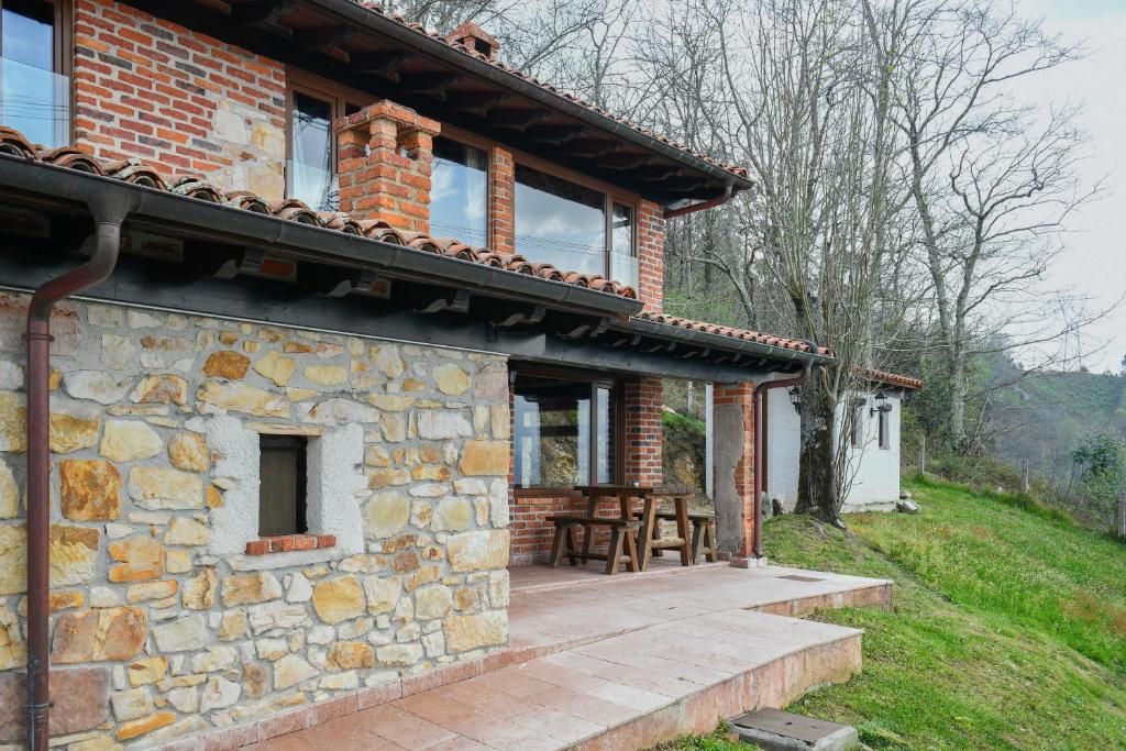 a stone house with a wooden deck in front of it at Apartamentos La Cabaña del Cerro Alto in Beceña