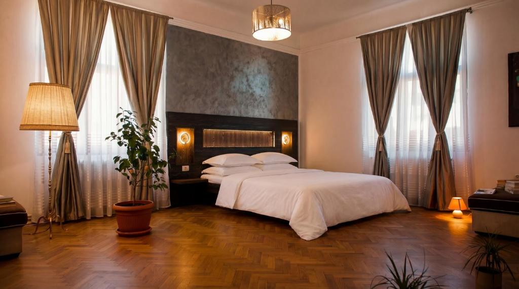 a bedroom with a large white bed and windows at Tivoli Apartament in Sebeş
