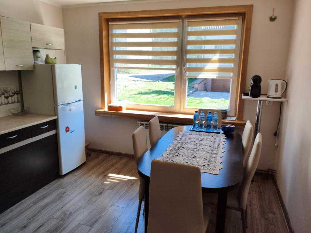 a kitchen with a blue table with chairs and a window at Apartament Przy Puszczy Białowieskiej in Hajnówka