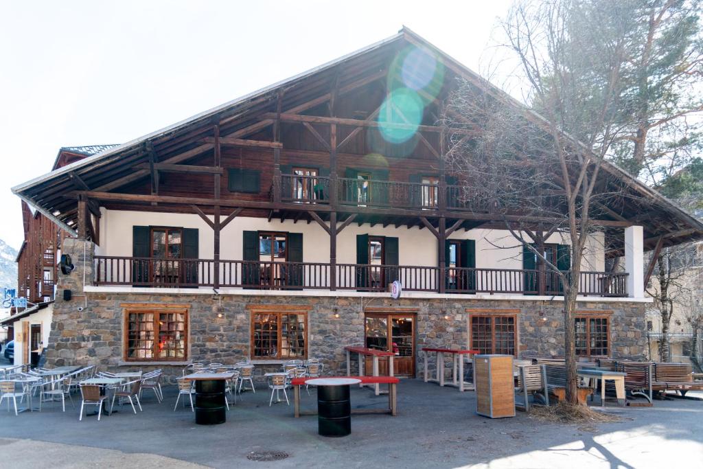 a building with tables and chairs in front of it at BodyGo Hostel Briançon in Briançon