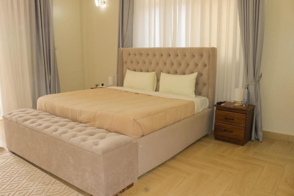 a bedroom with a large bed and a night stand at Residence Six Sigma in Entebbe