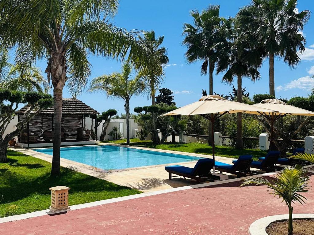 a swimming pool with chairs and umbrellas next to a resort at Villa Oasis Hammamet in Hammamet