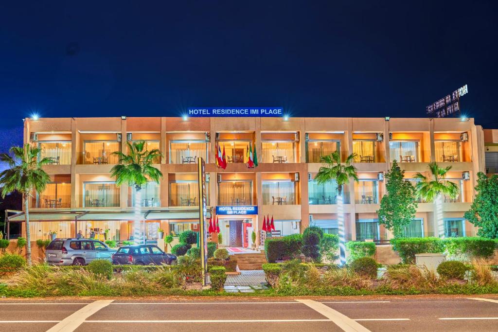 a large building with palm trees in front of it at Hôtel Imi Plage in Agadir