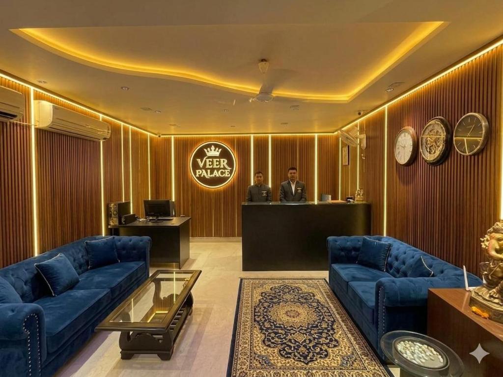 a lobby with blue couches and a man standing at a desk at HOTEL VEER PALACE By GREYSKY NEAR AIIMS DELHI in New Delhi