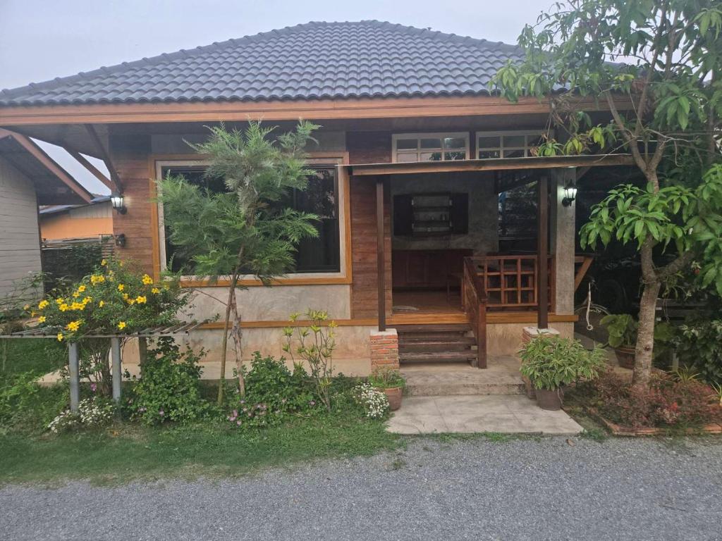 a wooden house with a porch and a staircase at Cocoa Hut in Mae Chan