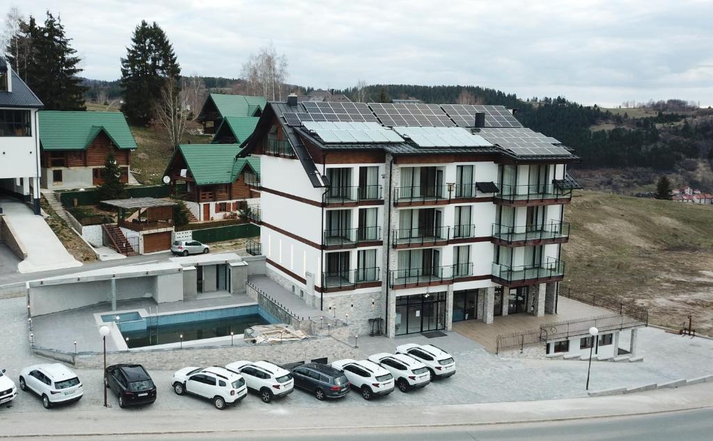 a large white building with cars parked in a parking lot at Meandri in Nova Varoš