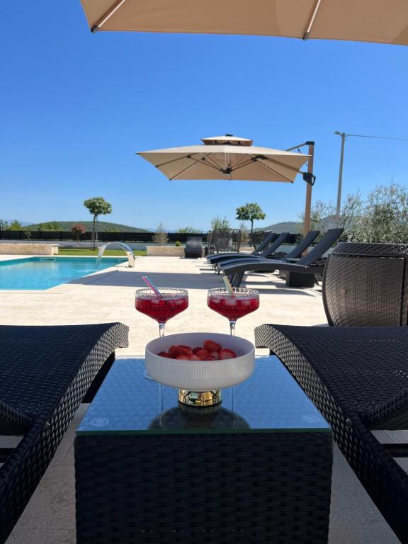 a table with two wine glasses on top of it at Villa DEL SOLE with Heated Saltwater Pool, Jacuzzi and Sauna in Ljubuški