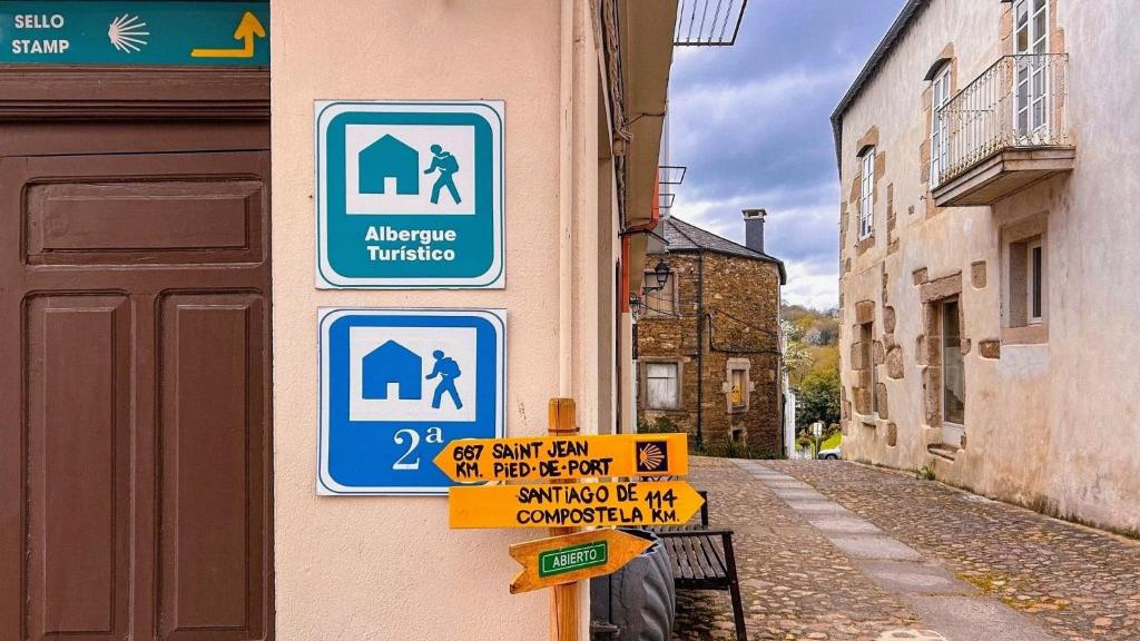 a group of signs on the side of a building at Albergue Mayor in Sarria