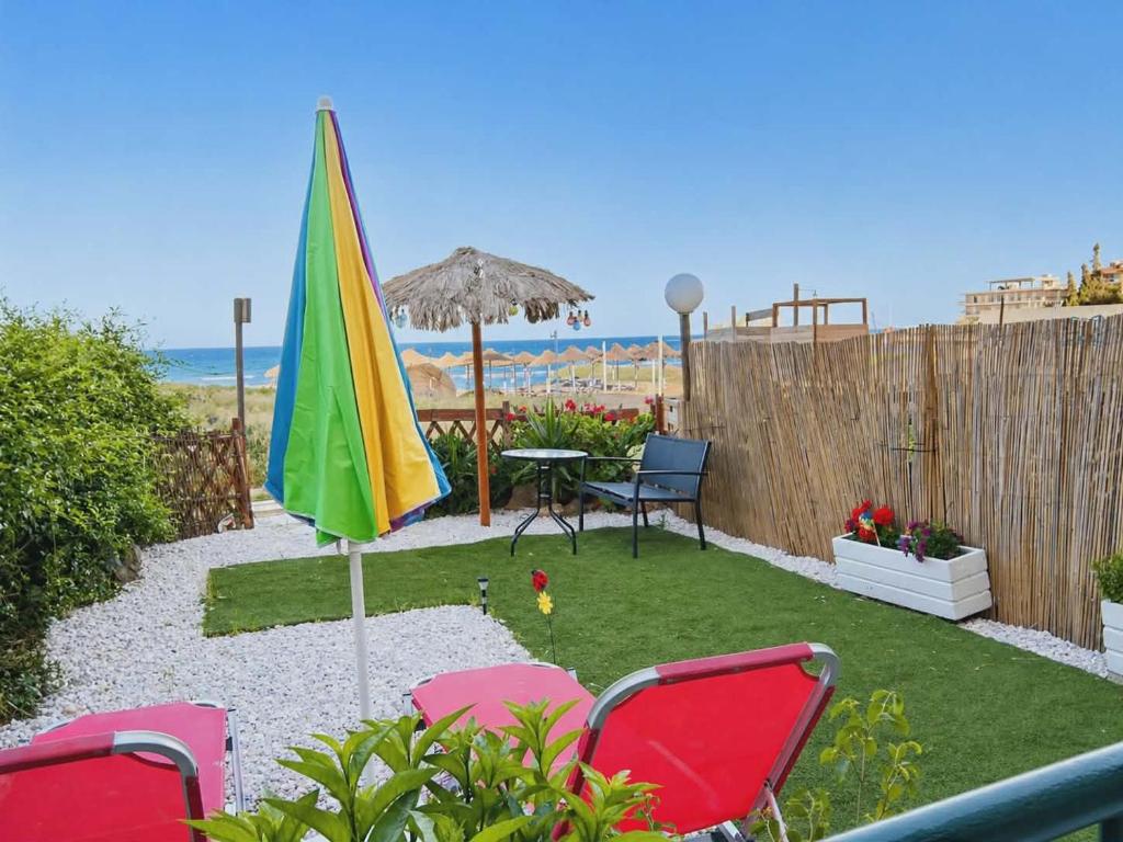 a patio with a table and chairs and an umbrella at ON THE SAND apartment in Artemida