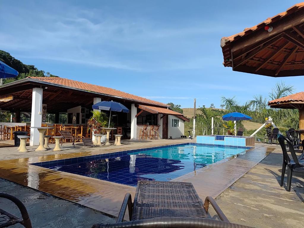 a swimming pool with chairs and umbrellas in a resort at Pousada irmãos Oliveira in Lindóia