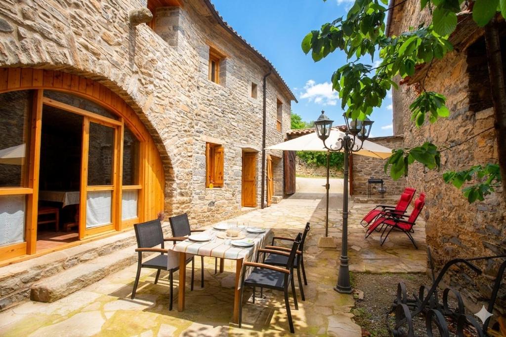a patio with a table and chairs and an umbrella at Casa rural La Masadría in Mondot