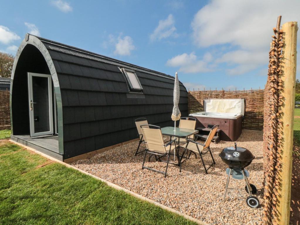 a black shed with a table and chairs and a grill at Starlight Sanctuary in Malton