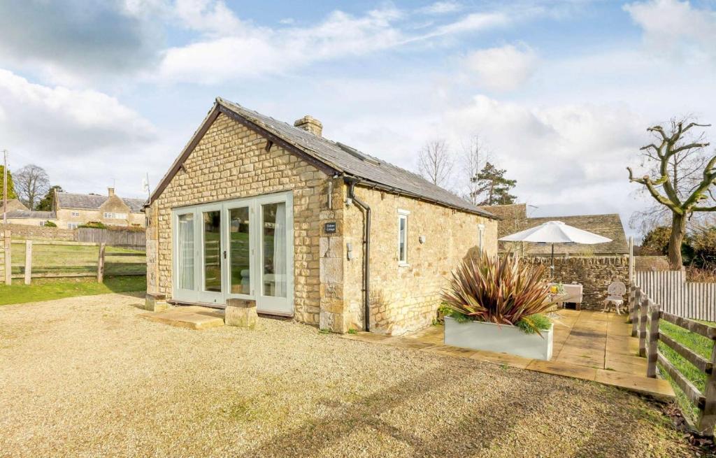 a brick cottage with a patio and an umbrella at Oxbow Cottage in Stow on the Wold