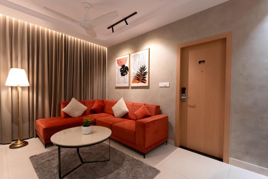 a living room with a red couch and a table at Dlite Rivera Premium Hotel Apartments in Bangalore