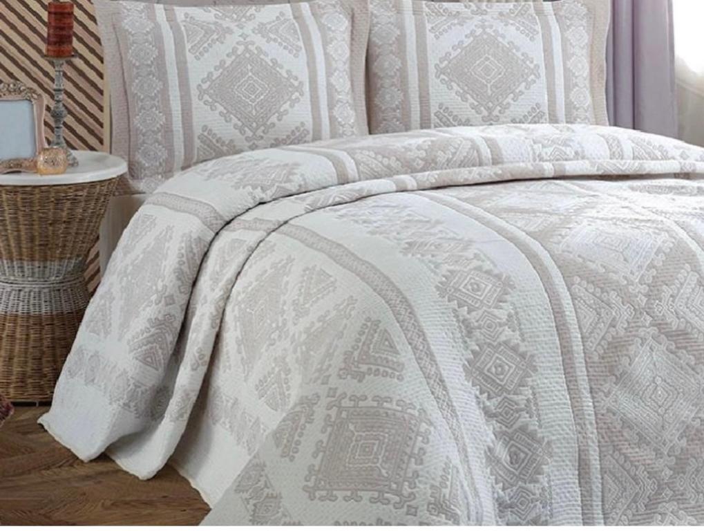 a bed with a white comforter on top of it at Grecia's Dhermi in Dhërmi
