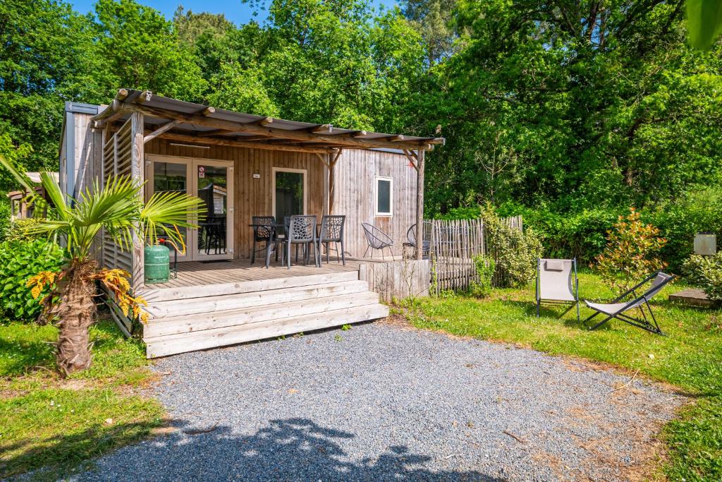 a small cabin with a deck and a table and chairs at Camping Le Paradis Médoc in Saint-Laurent-de-Médoc