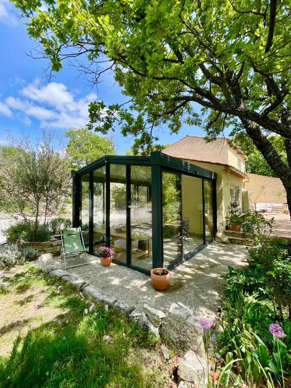 a glass house with a chair in a garden at L'évidence en Provence in Vachères