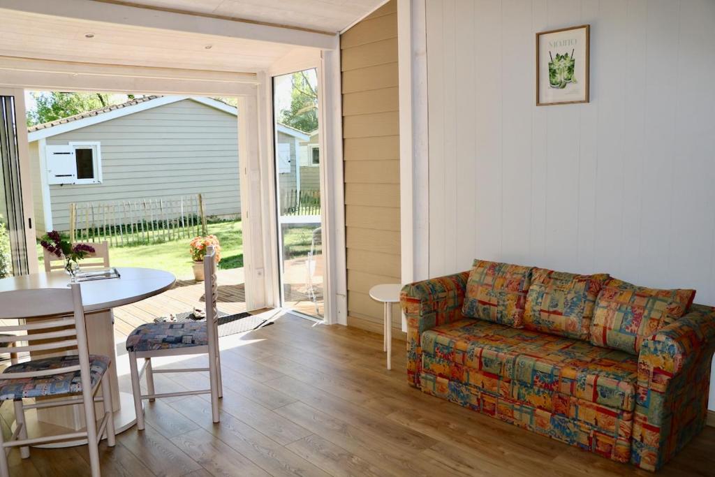 a living room with a couch and a table at Chalet Au Petit Bonheur Piscine & Domaine calme in Rivières
