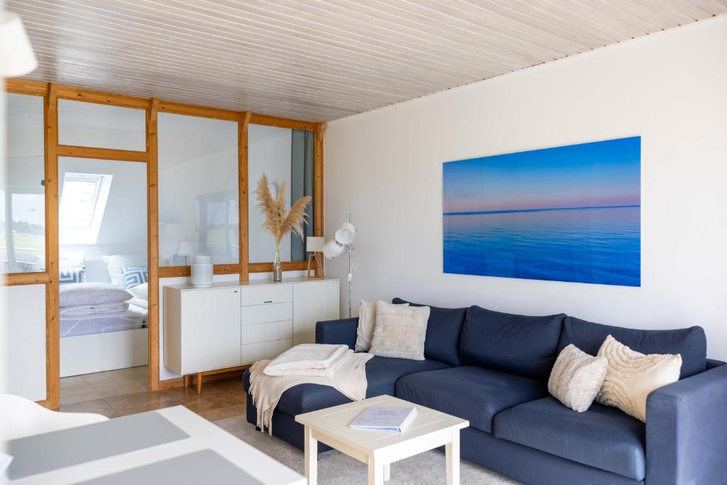 a living room with a blue couch and a bedroom at Sonnenkoje in Fehmarn