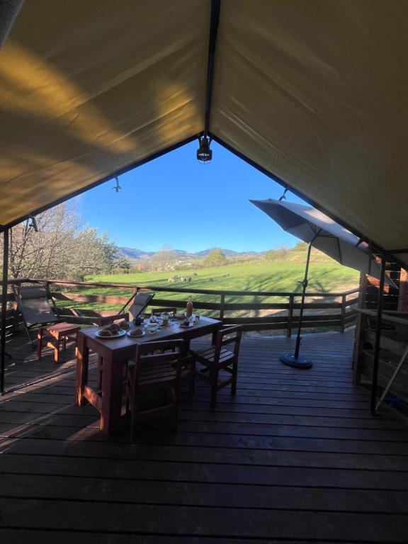a tent with a table and chairs on a deck at Domaine Solio - Lodge isolée, nature, animaux in Satillieu