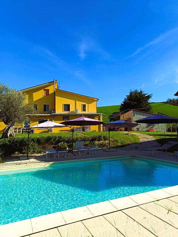 a swimming pool in front of a house with umbrellas at Villa Ferranti Abruzzo in Montefino