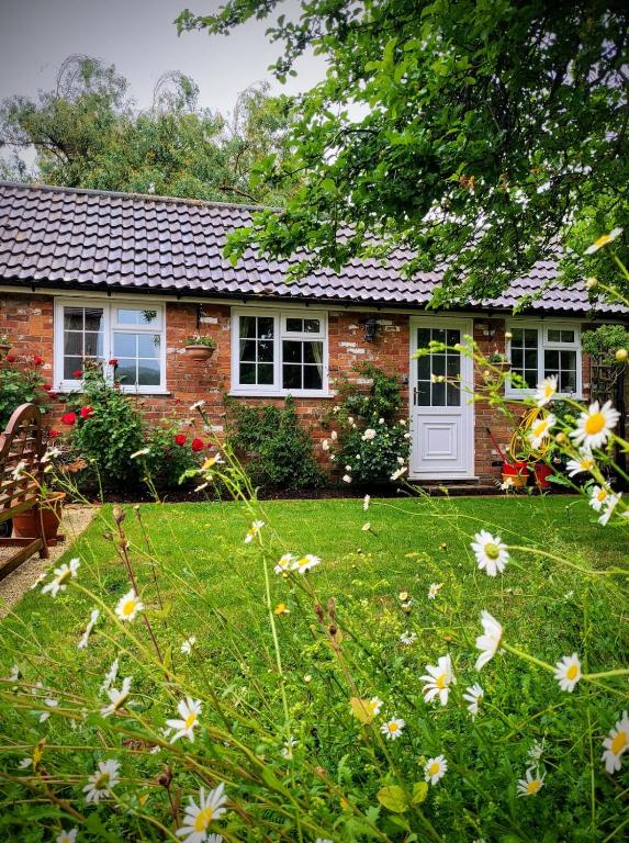 a brick house with a yard with flowers at Apple Tree View in Coulston