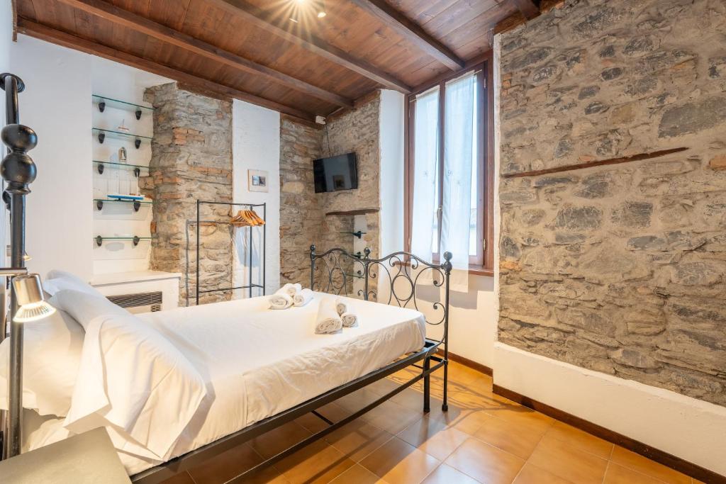 a bedroom with a bed and a stone wall at Historic Borgo Lake Como Campidoglio 5 in Lenno