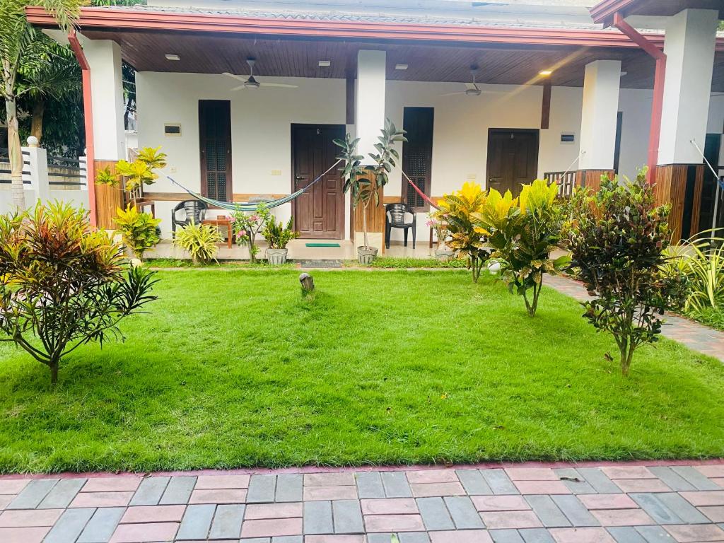 a dog standing in the grass in front of a house at Baywings Rooms in Arugam Bay