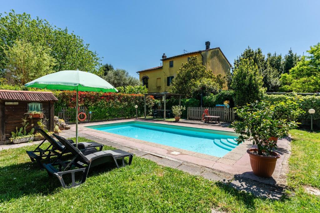 a swimming pool with two lawn chairs and an umbrella at Casa Anita Lucca in Lucca