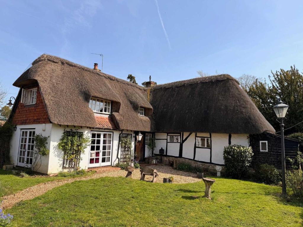 a thatched house with a grass roof at Mesopotamia Cottage in Clifton Hampden